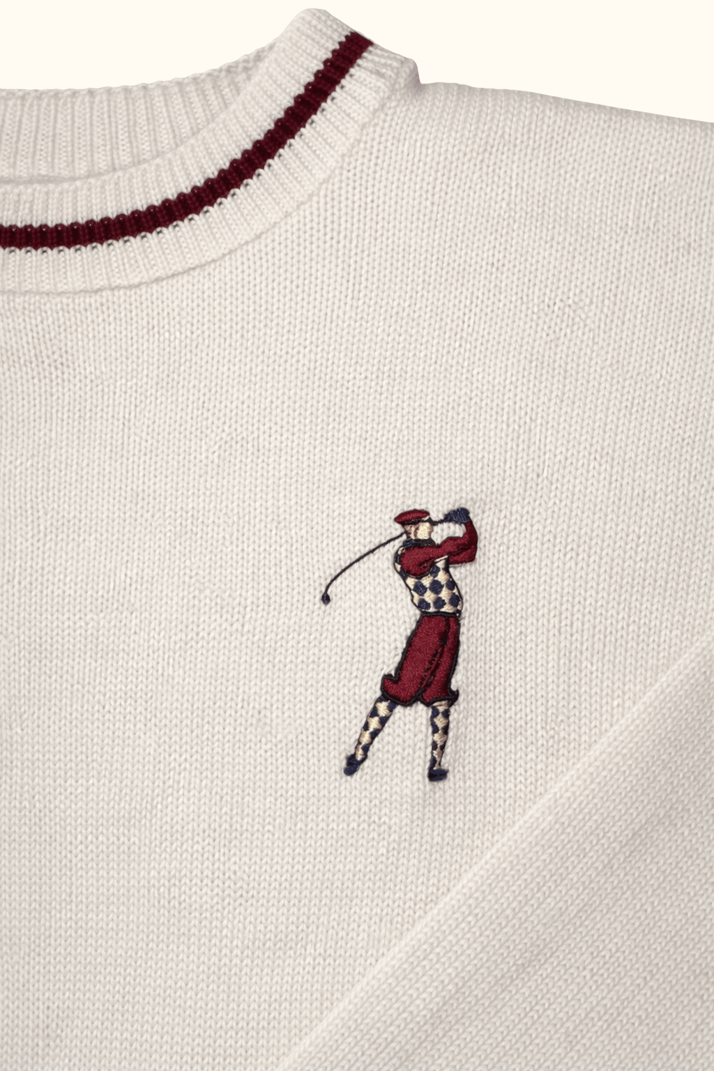 Close-up of a white sweater with a embroidered polo player design on a white background