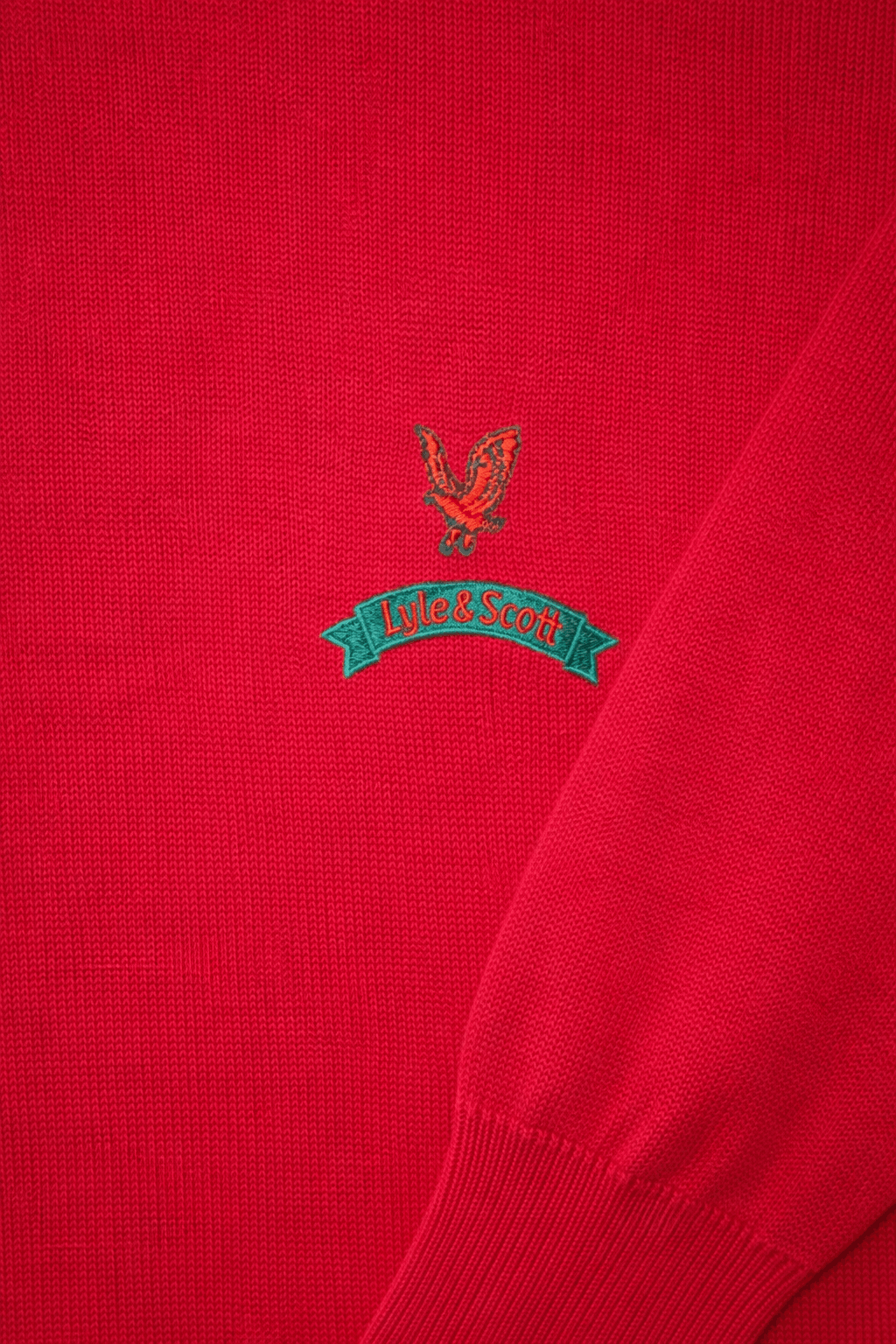 Close-up of a red sweater with a logo and text on the chest.