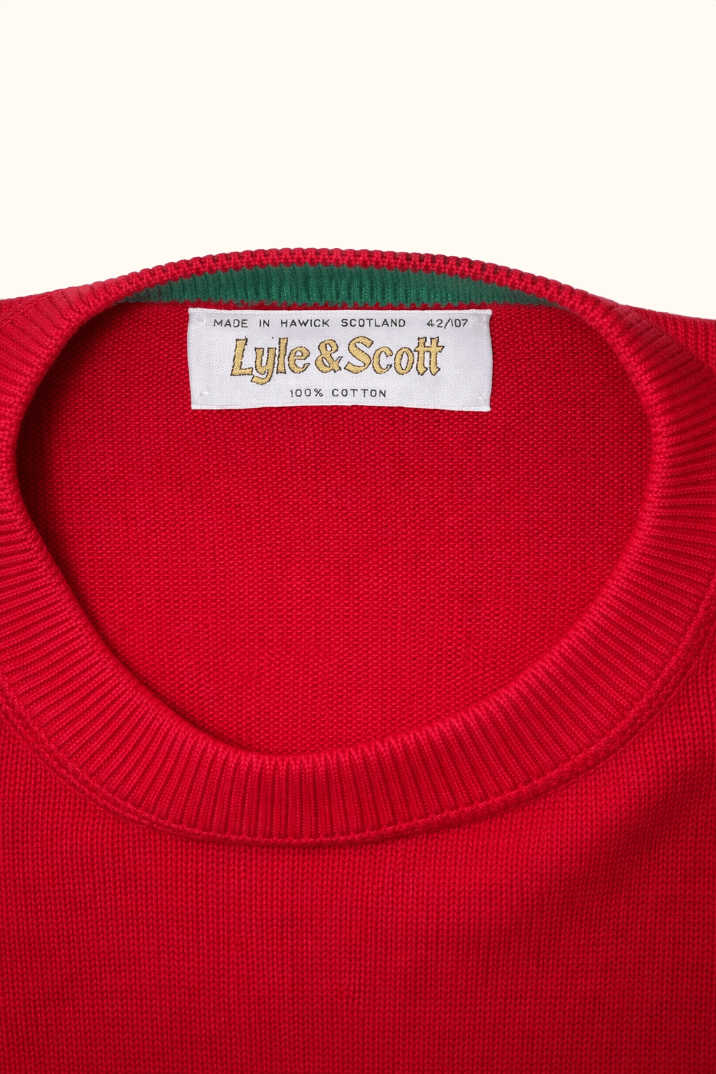 Close-up of a red sweater with a visible Lyle & Scott label on a white background